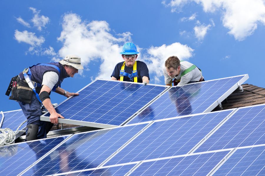 Workers installing solar panels on the roof